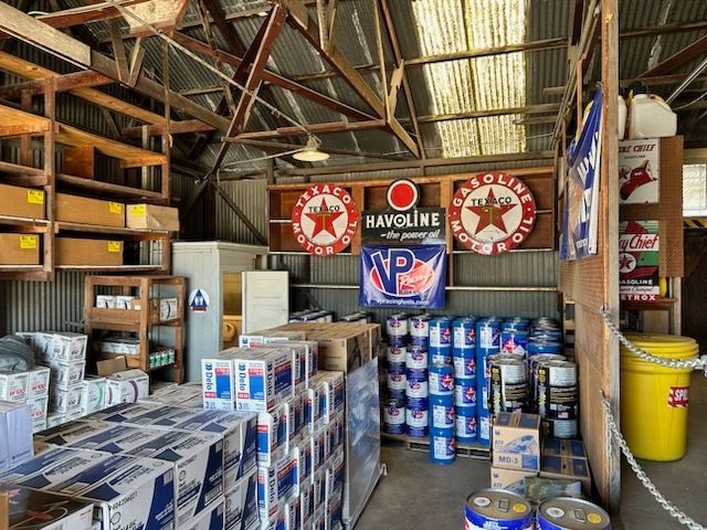 A warehouse filled with lots of boxes and barrels of oil.