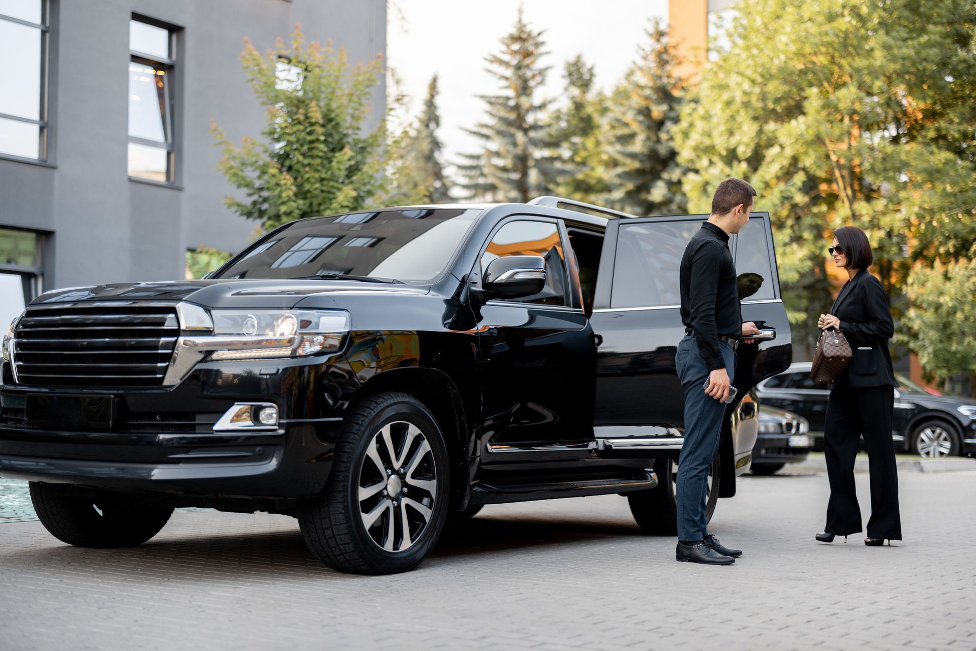 A man and a woman are standing next to a black car.