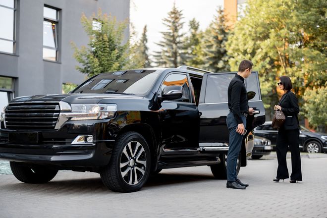 A man and a woman are standing next to a black car.