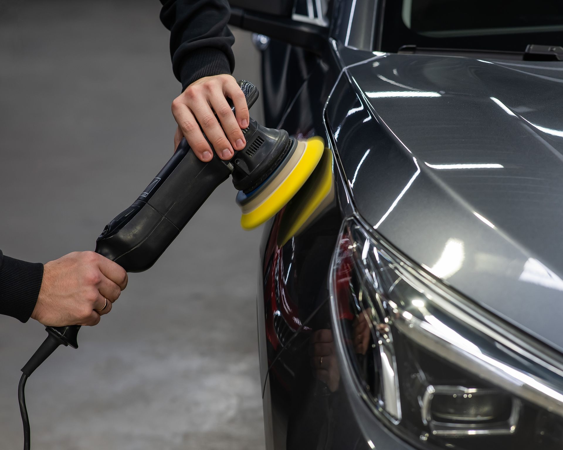 A person is polishing a car with a machine.