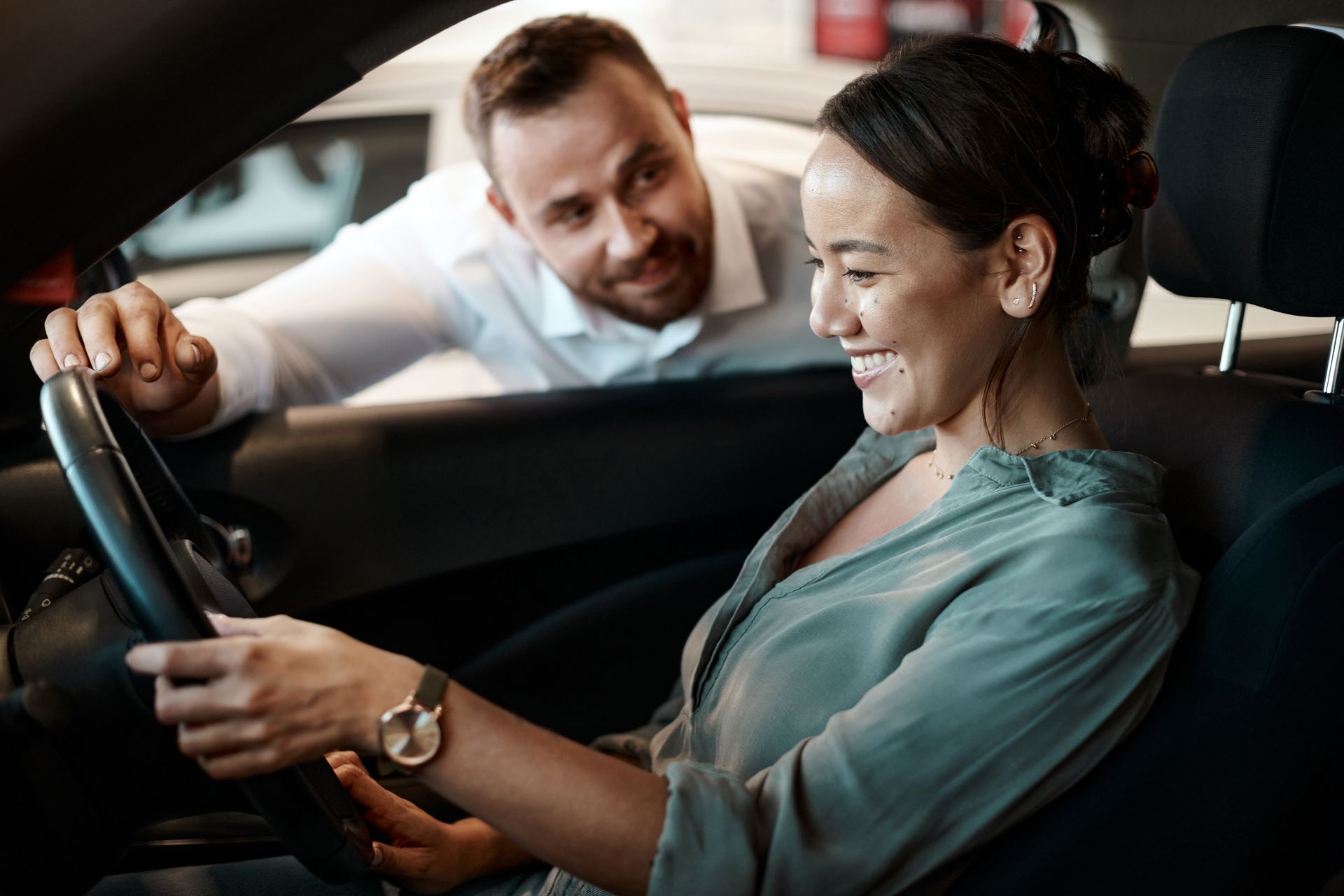 A woman is sitting in a car with a man standing behind her.