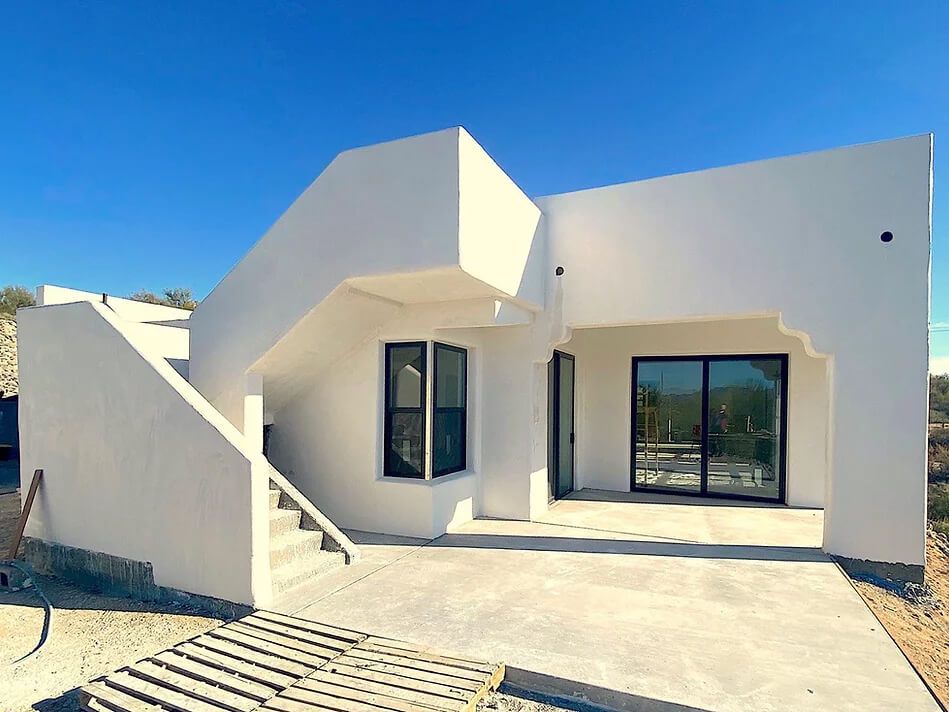 A white house with stairs leading up to it and a blue sky in the background.