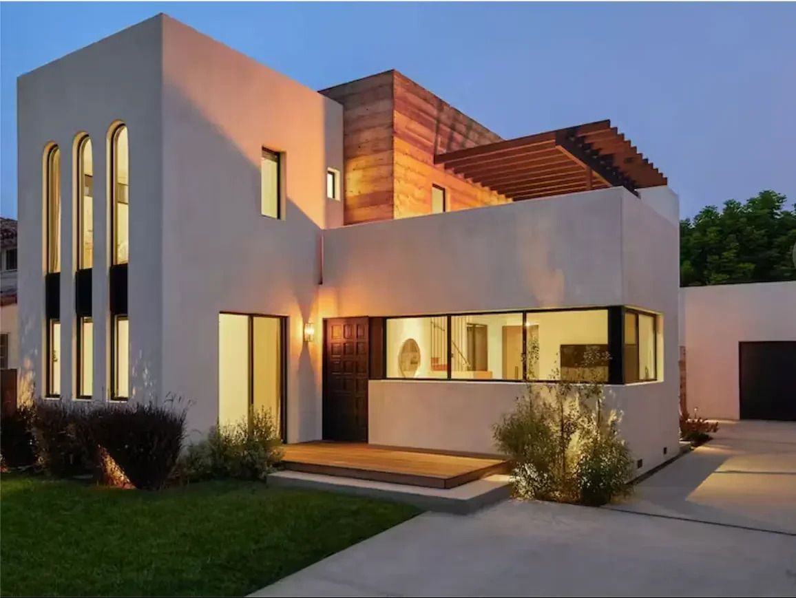 A house with a lot of windows is lit up at night.