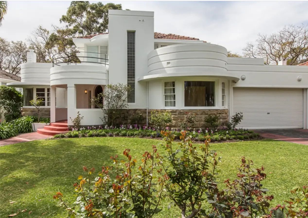 A large white house with a lush green lawn in front of it.