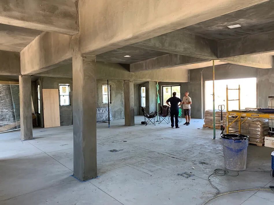 A group of people are standing in a large room under construction.
