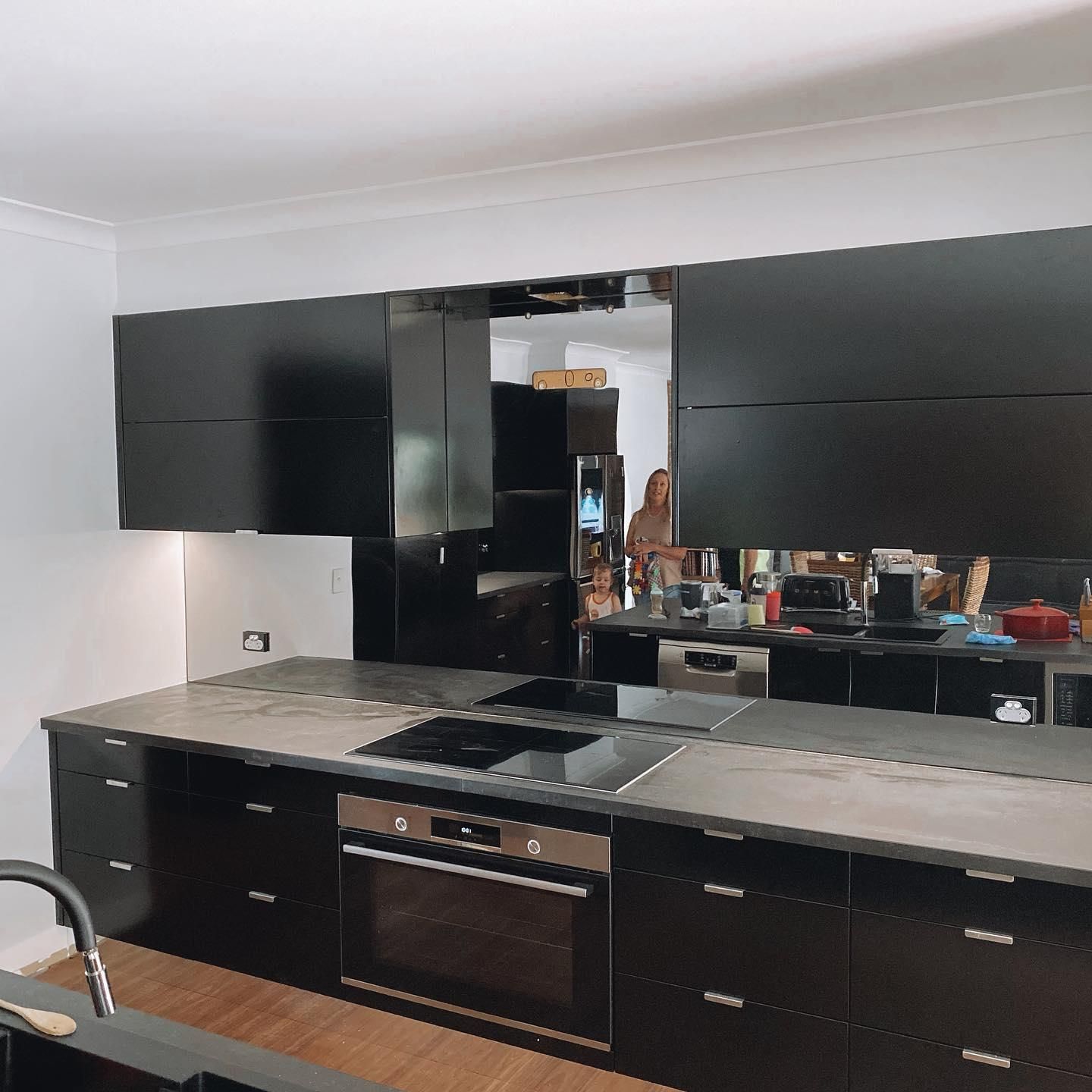 A Kitchen with Black Cabinets and A Stove Top Oven — Distinctive Glass In Forster, NSW