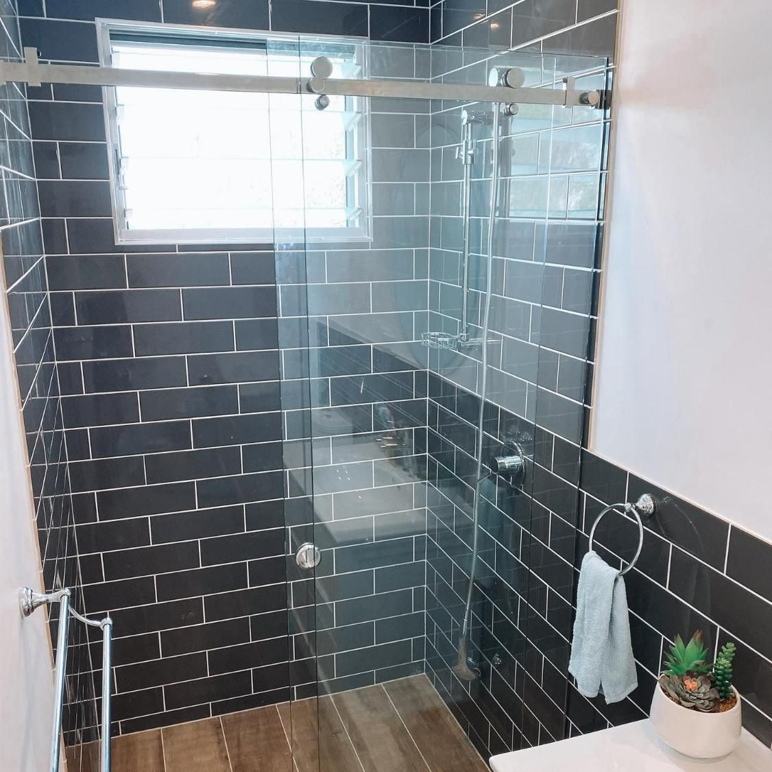 A Bathroom with Black Tiles and A Sliding Glass Shower Door — Distinctive Glass In Toormina, NSW