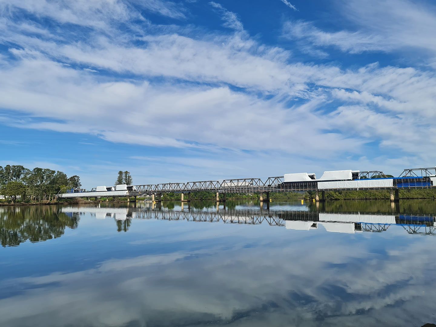 A Bridge Over a Body of Water with A Blue Sky — Distinctive Glass In Taree, NSW