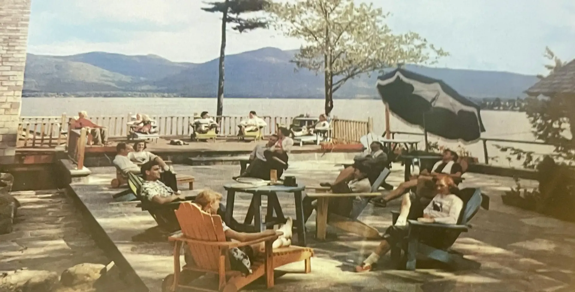 A group of people are sitting in chairs on a patio overlooking a lake.