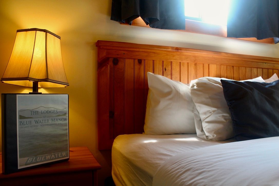 A bed with white sheets and black pillows next to a lamp