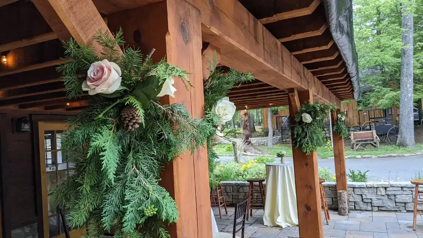 A wooden pergola with flowers and greenery hanging from it.