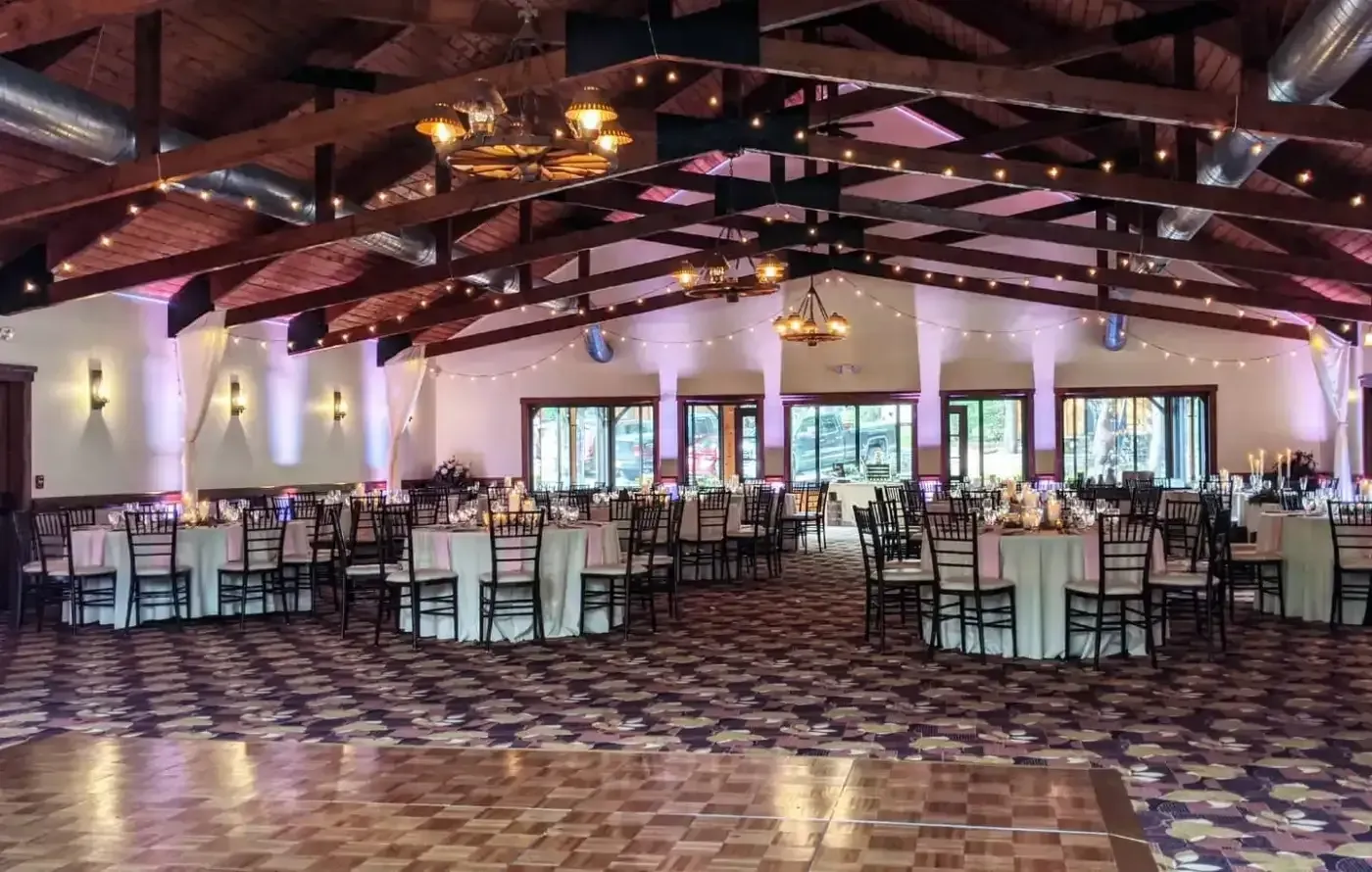 A large room with tables and chairs set up for a wedding reception.