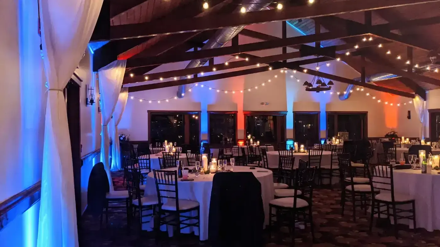 A large room with tables and chairs set up for a wedding reception.