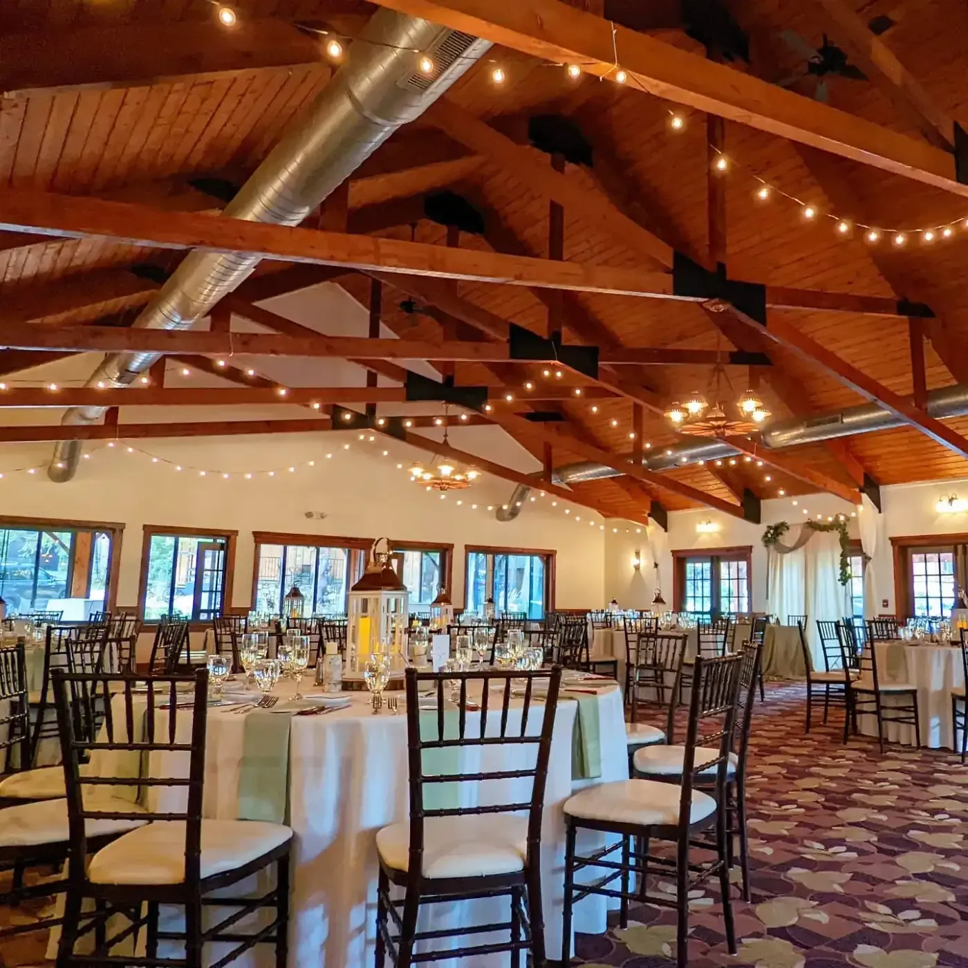 A large room with tables and chairs set up for a wedding reception