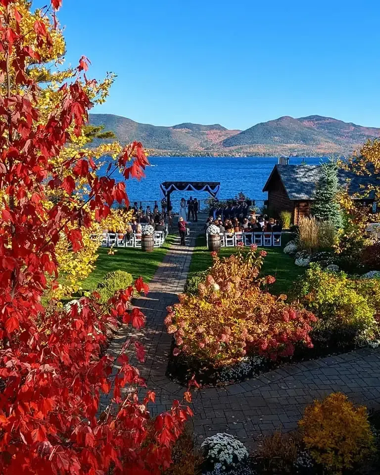 A wedding ceremony is taking place in front of a lake with mountains in the background.