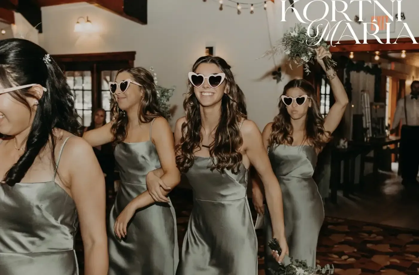 A group of bridesmaids wearing sunglasses are walking down a hallway.