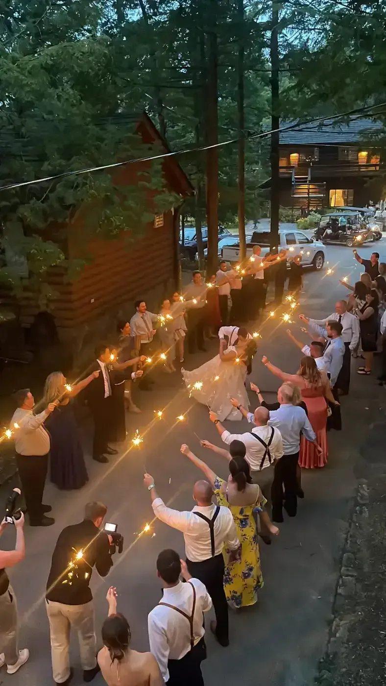 A group of people are standing in a line holding sparklers.