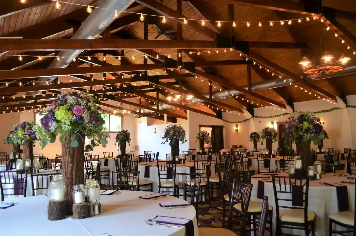 A large room with tables and chairs set up for a wedding reception.