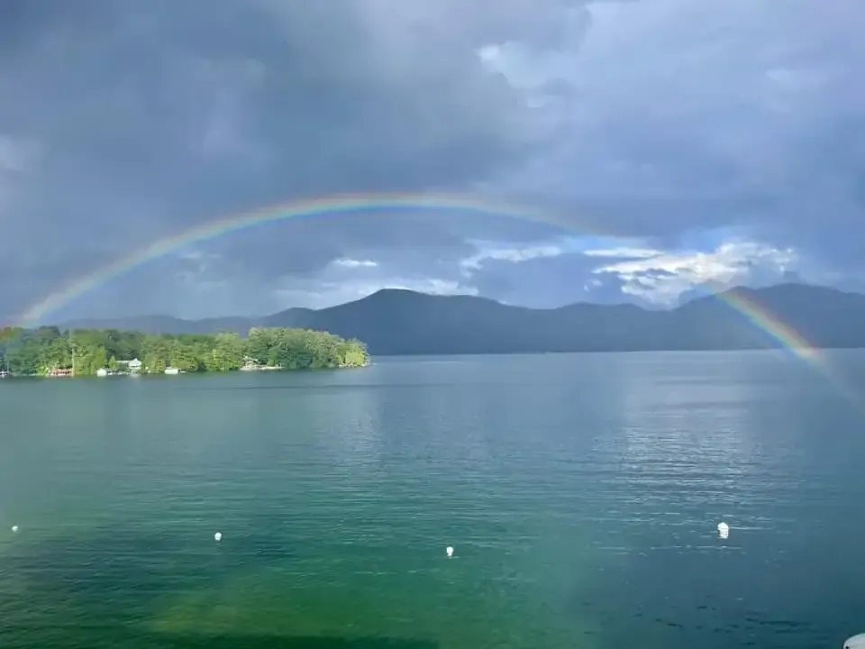 There is a rainbow over a lake with mountains in the background.