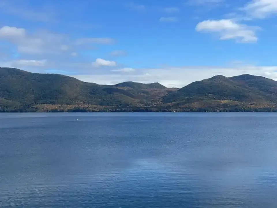 A large body of water surrounded by mountains on a sunny day.