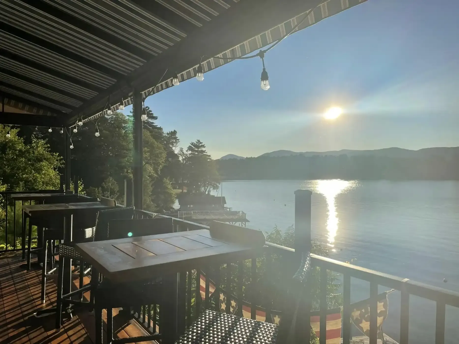 A balcony overlooking a lake with tables and chairs