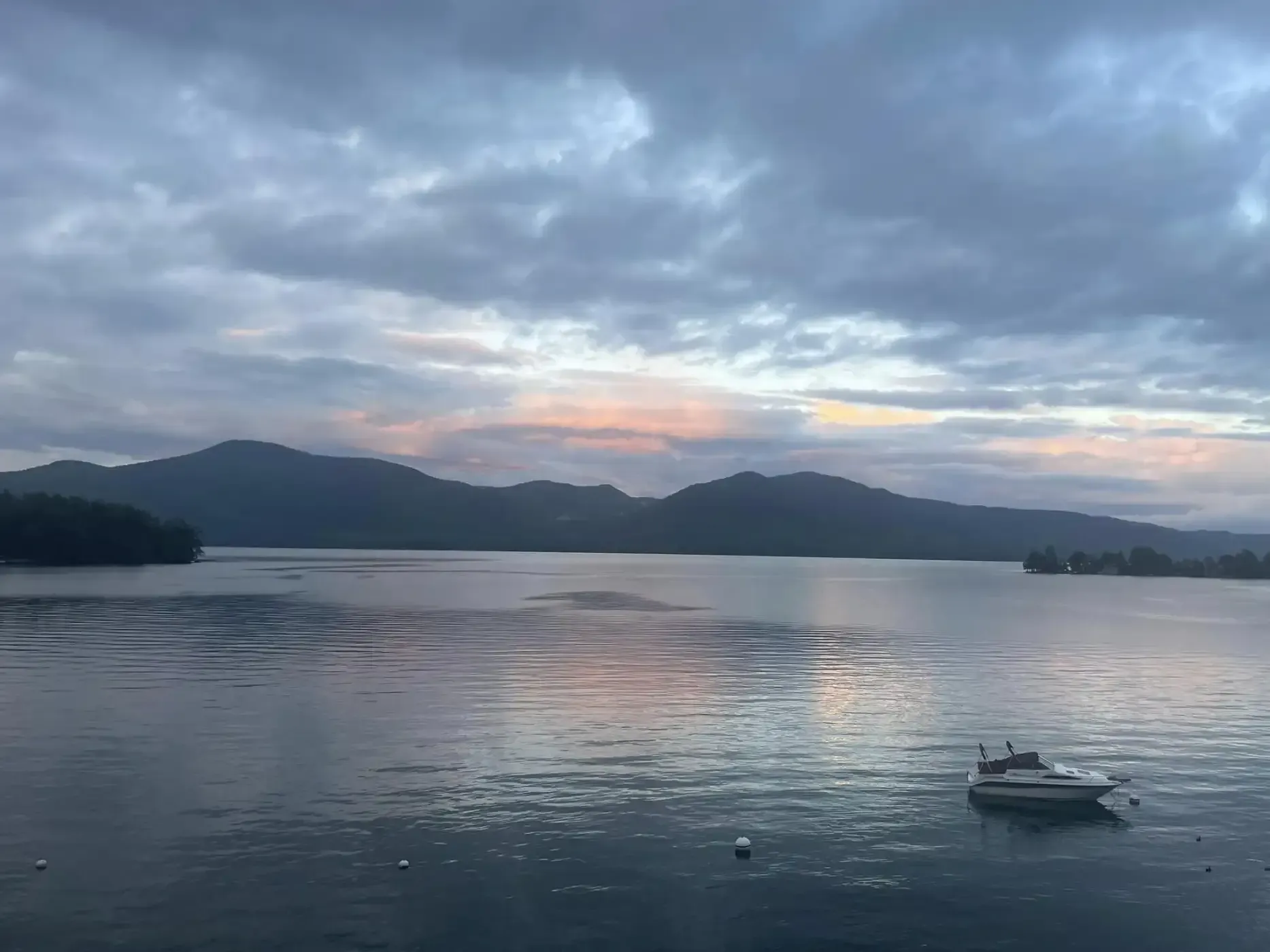 A boat is floating on a lake with mountains in the background.