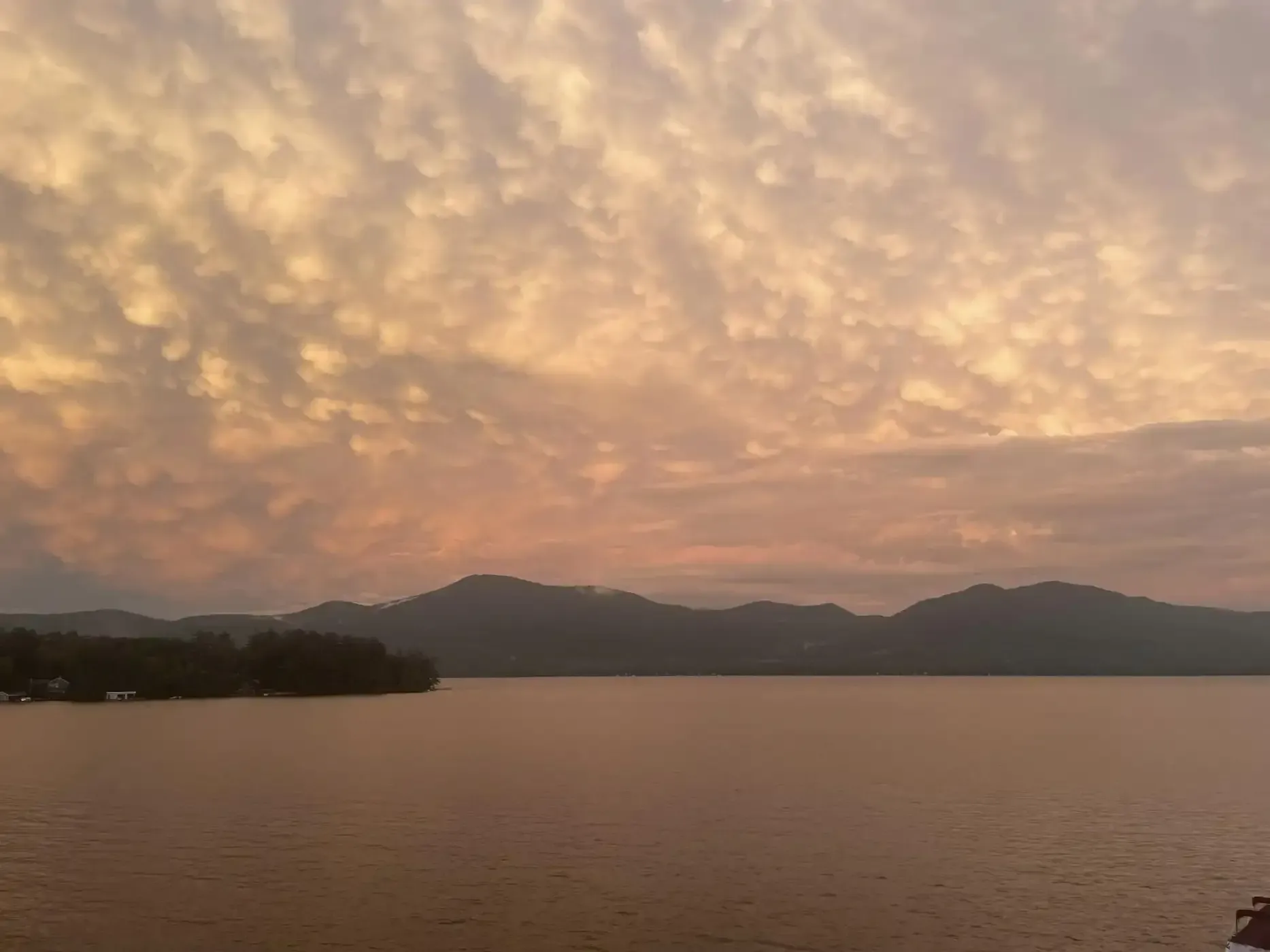 A sunset over a large body of water with mountains in the background.