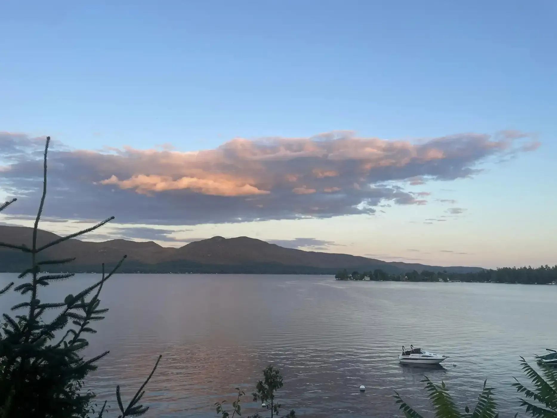 A boat is floating on a lake with mountains in the background