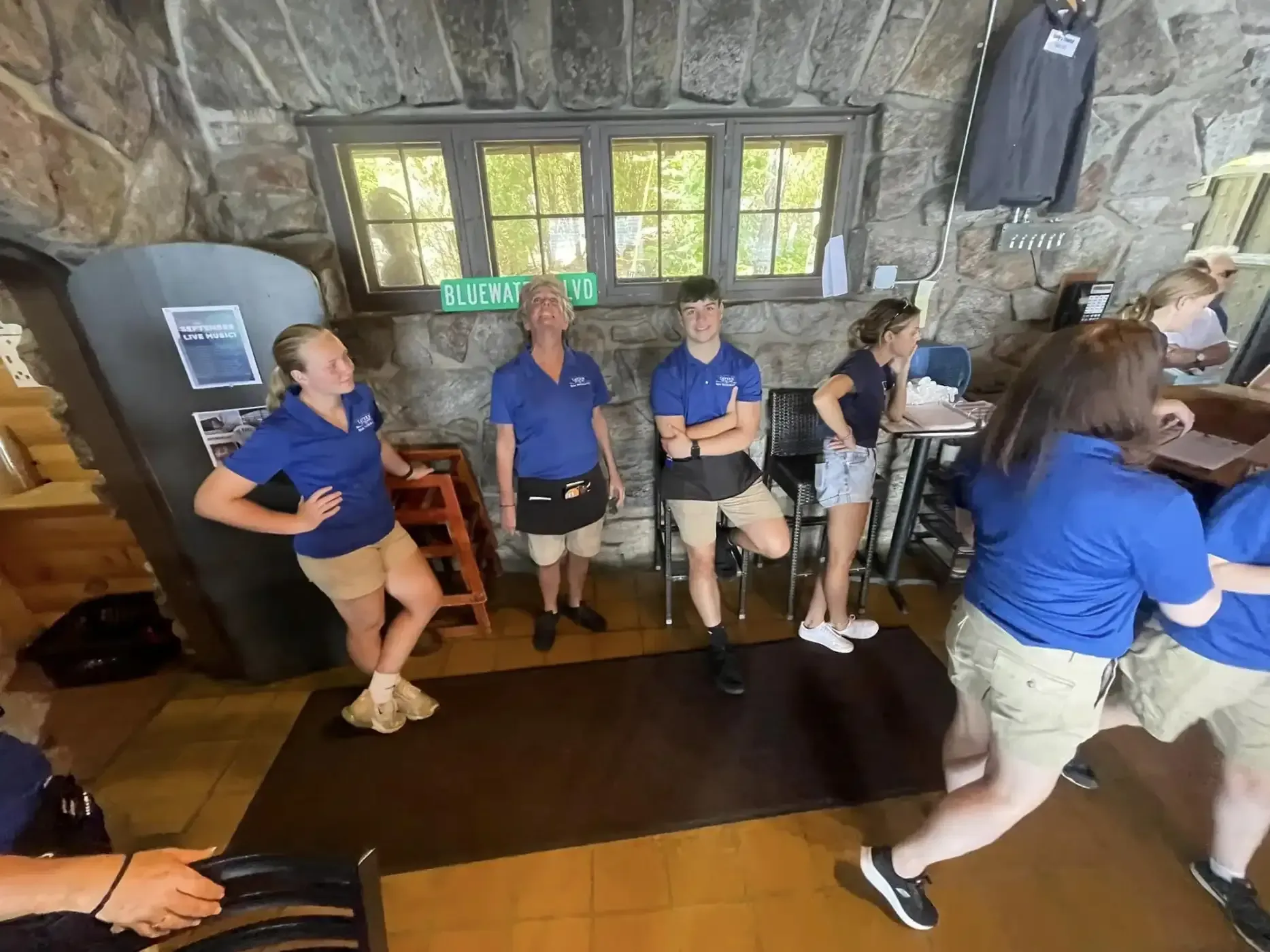 A group of people in blue shirts are standing in a room.