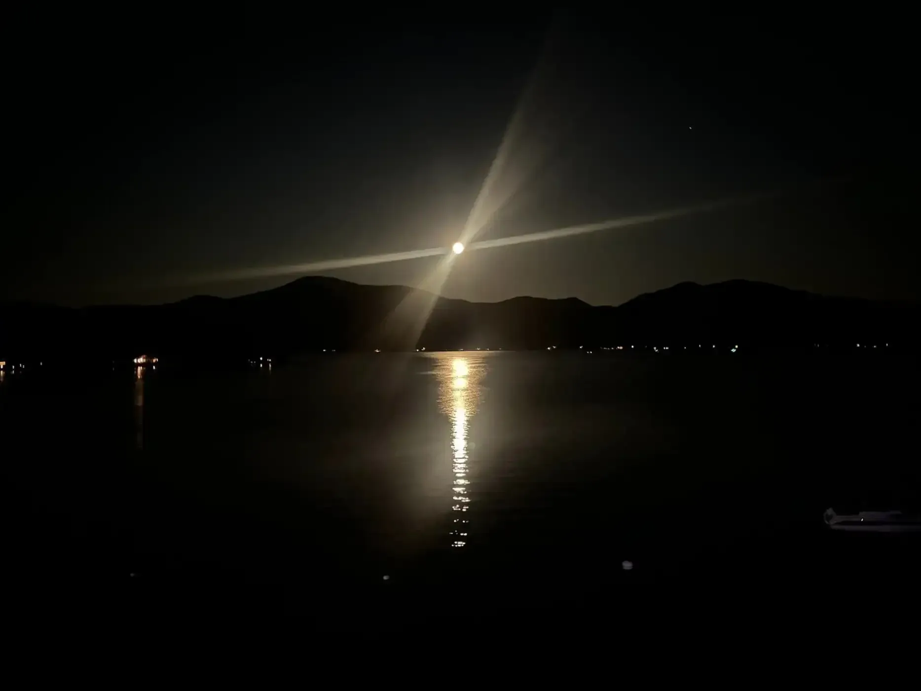 A full moon is shining over a lake at night.