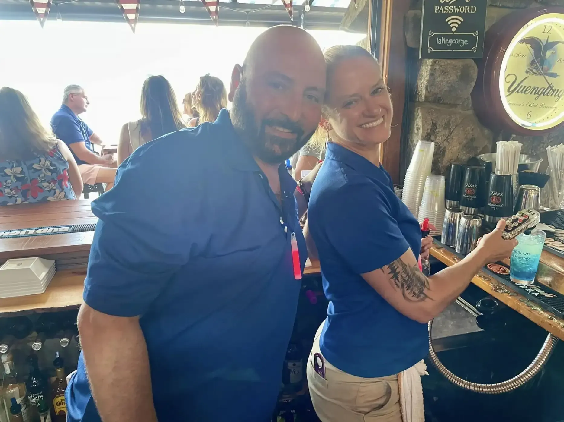 A man and a woman are standing next to each other in a bar.