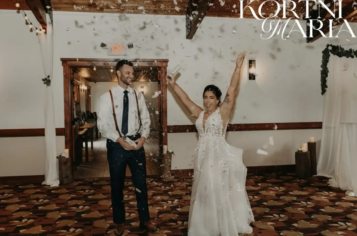 A bride and groom are standing in a room with their arms in the air.