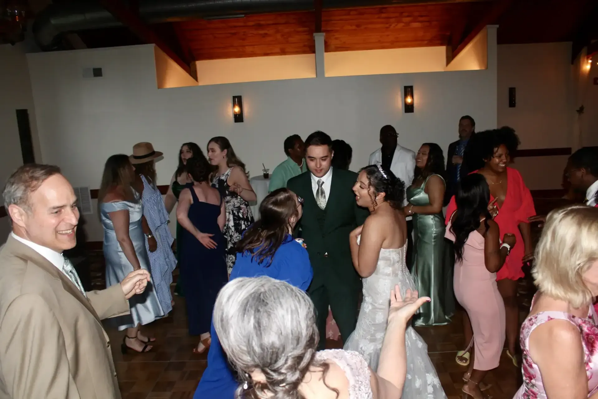A group of people are dancing in a room at a wedding reception.