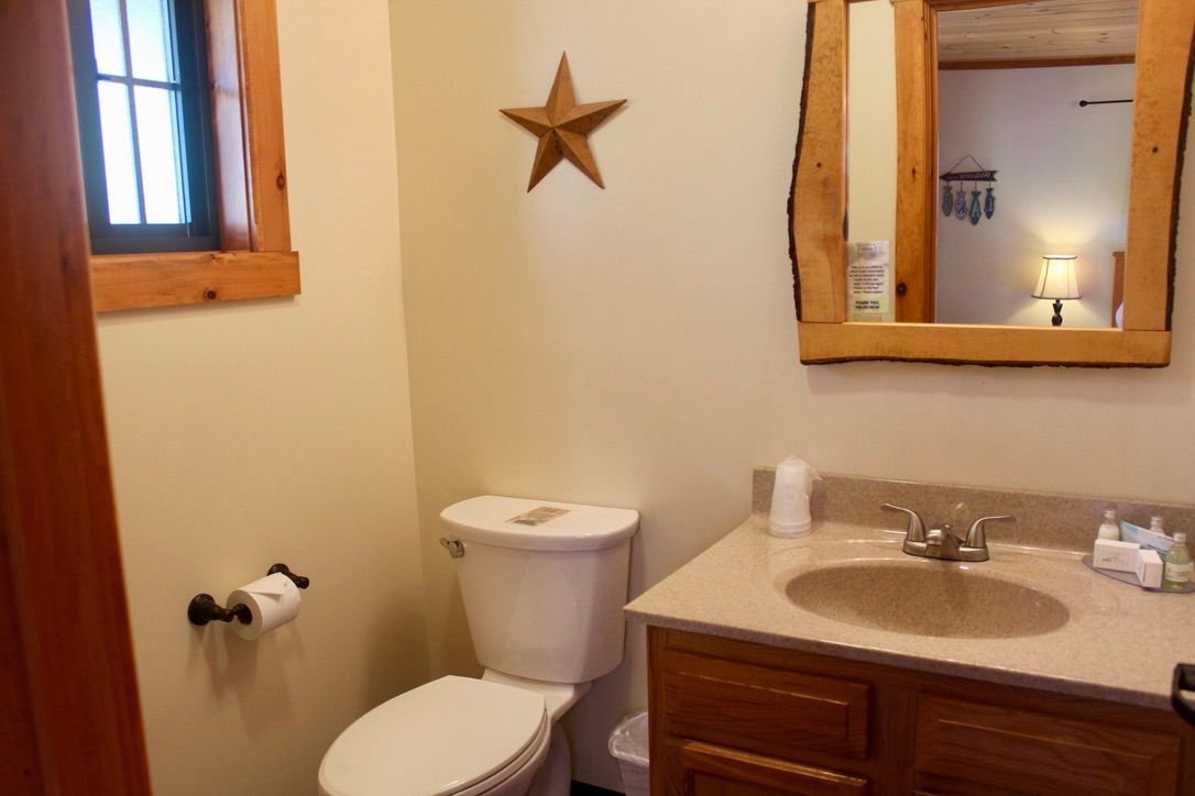 A bathroom with a toilet , sink , mirror and star on the wall.