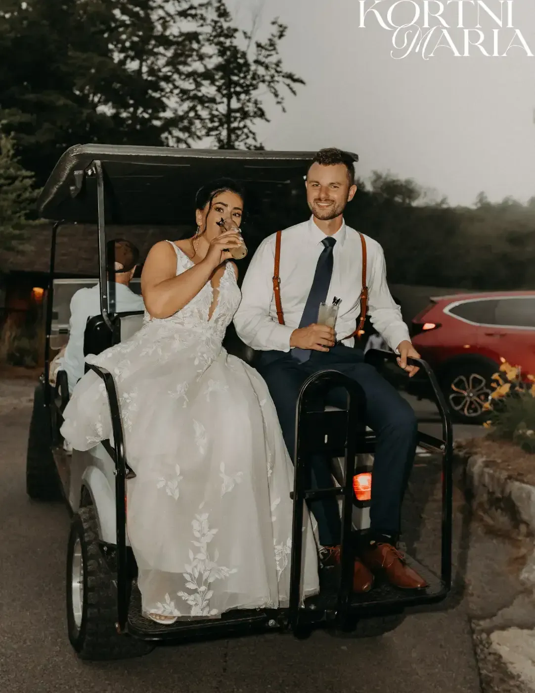 A bride and groom are riding in a golf cart