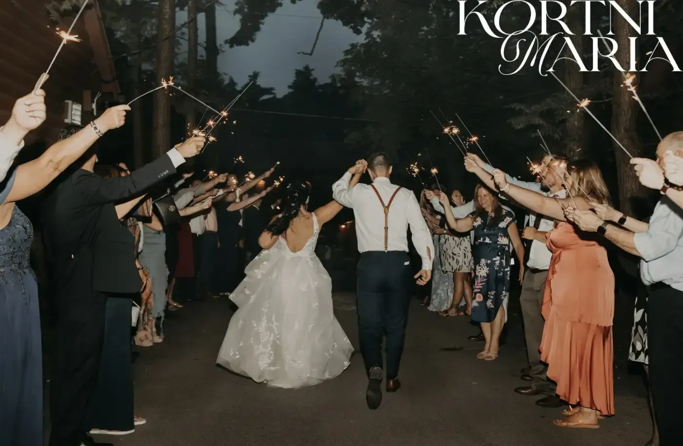 A bride and groom are walking through a tunnel of sparklers.
