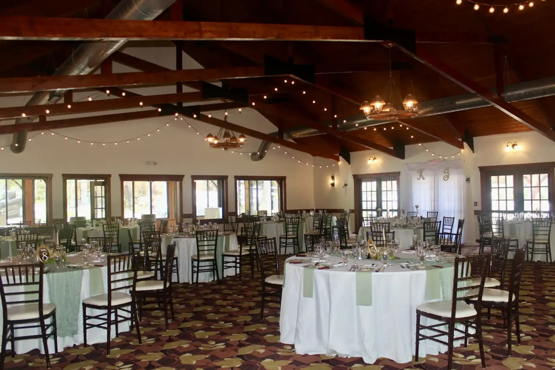 A large room with tables and chairs set up for a wedding reception.