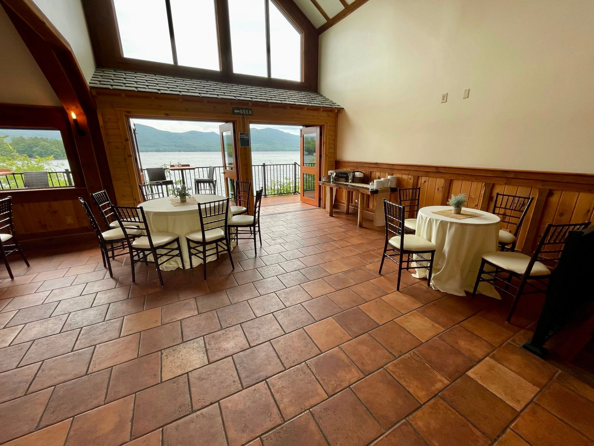 A large room with tables and chairs and a view of a lake.