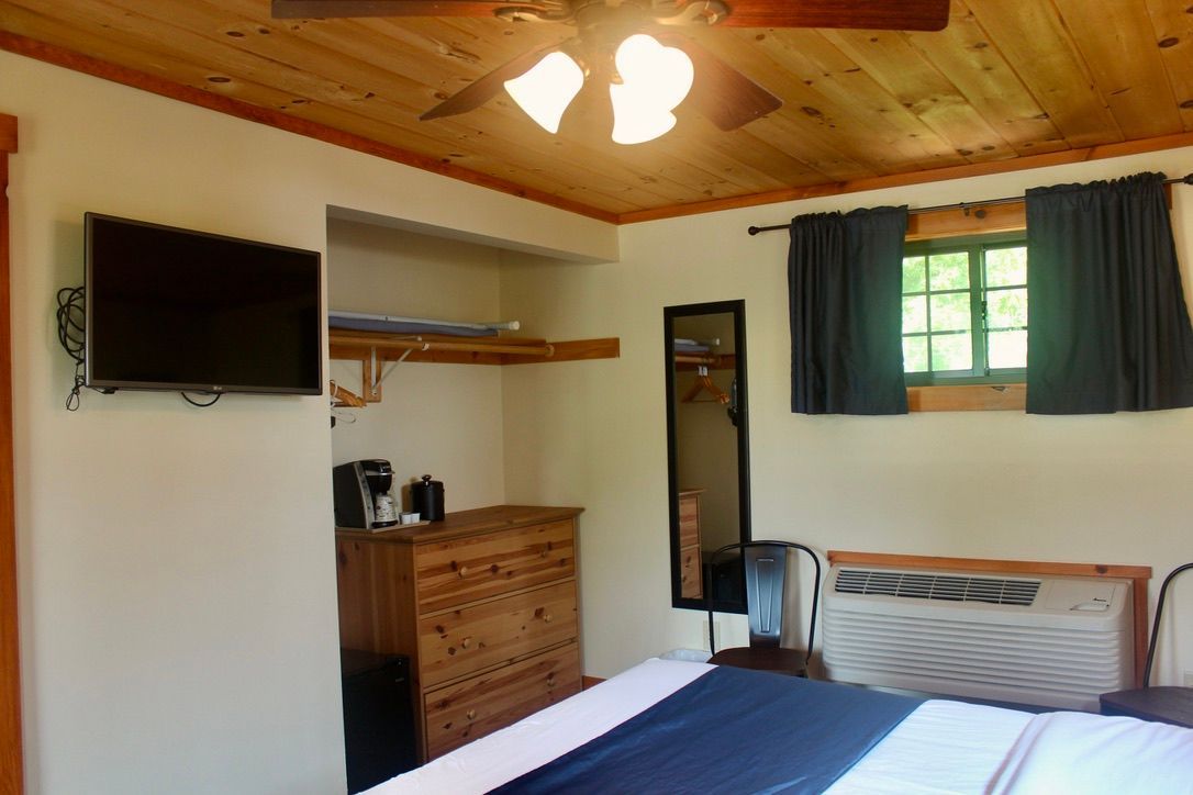 A bedroom with a bed , dresser , television and ceiling fan.