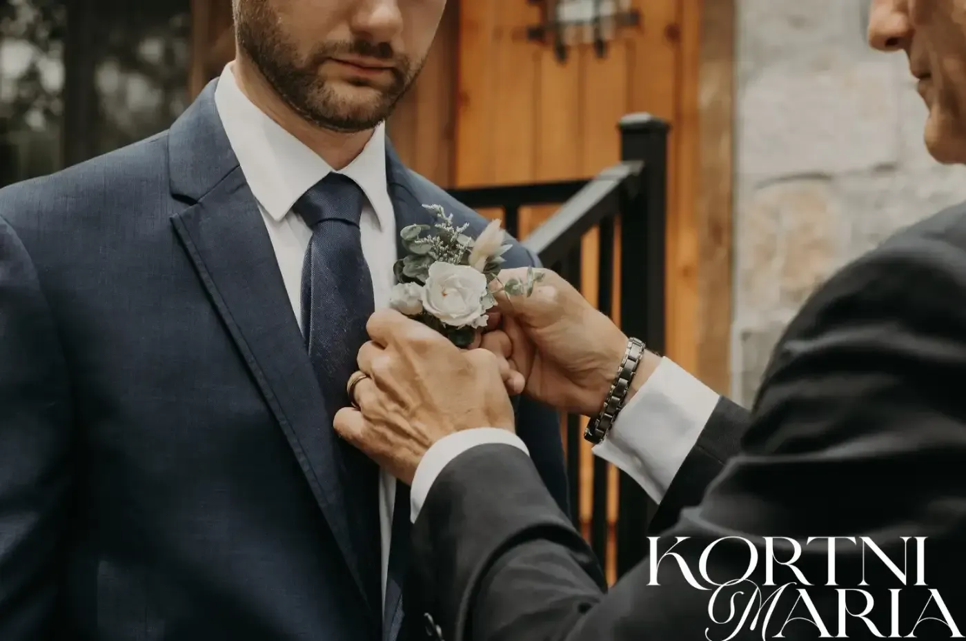 A man in a suit and tie is being helped by another man.