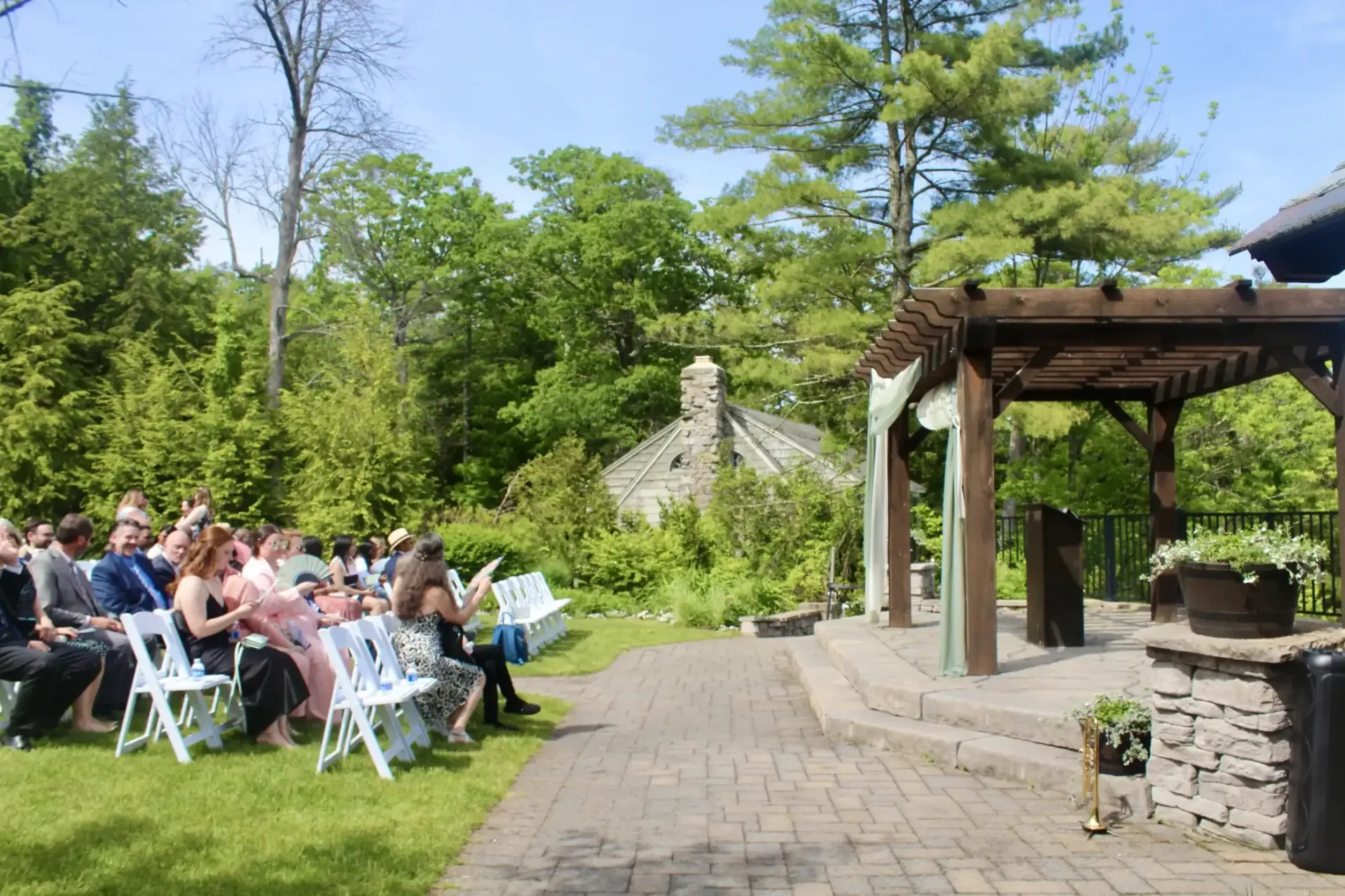 A group of people are sitting in chairs at a wedding ceremony under a gazebo.