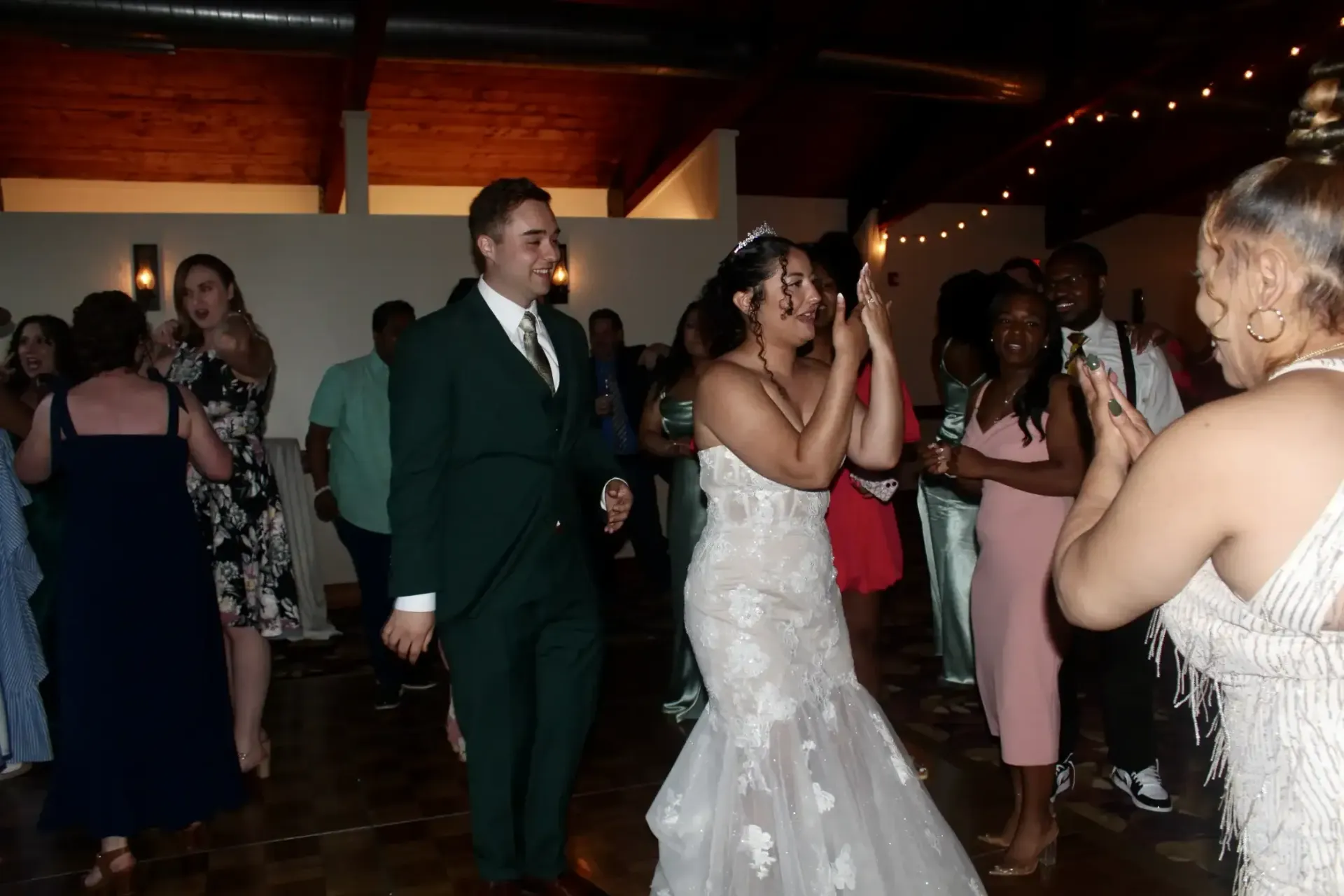 A bride and groom are dancing with their wedding guests at a wedding reception.