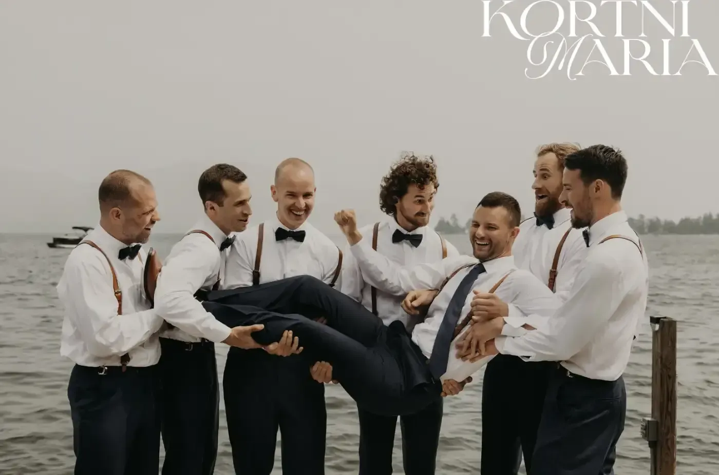 A group of men are holding a man in their arms over a body of water.