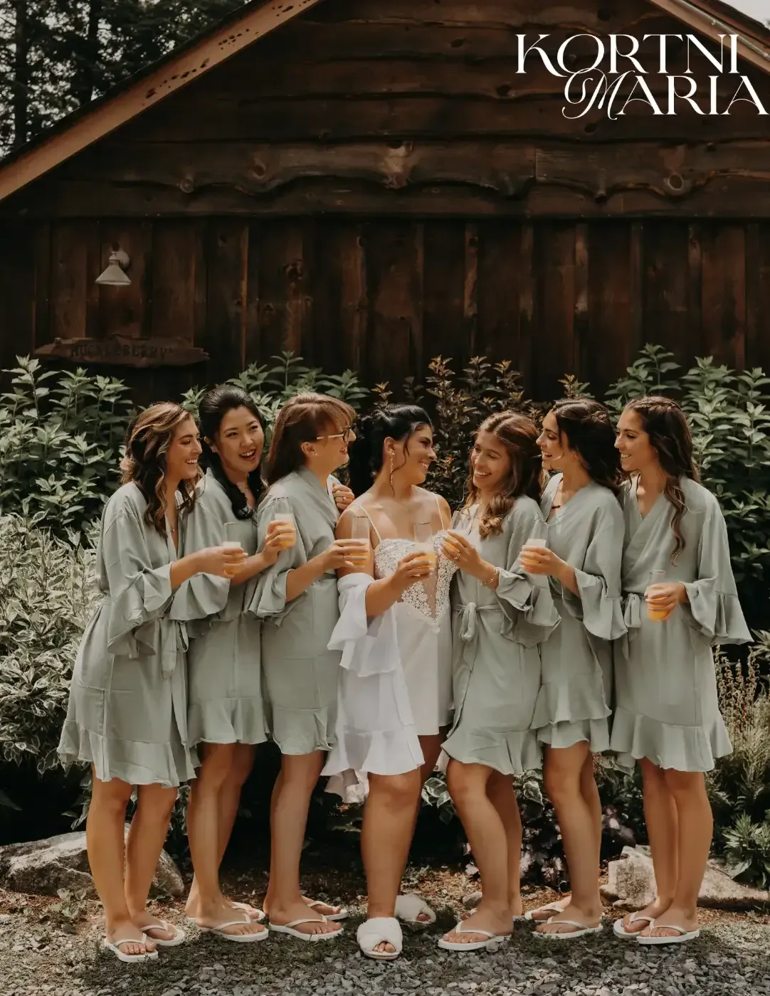 A bride and her bridesmaids are posing for a picture in front of a wooden building.