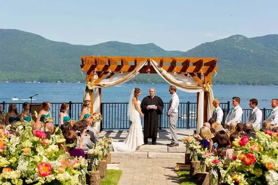 A bride and groom are getting married in front of a lake.