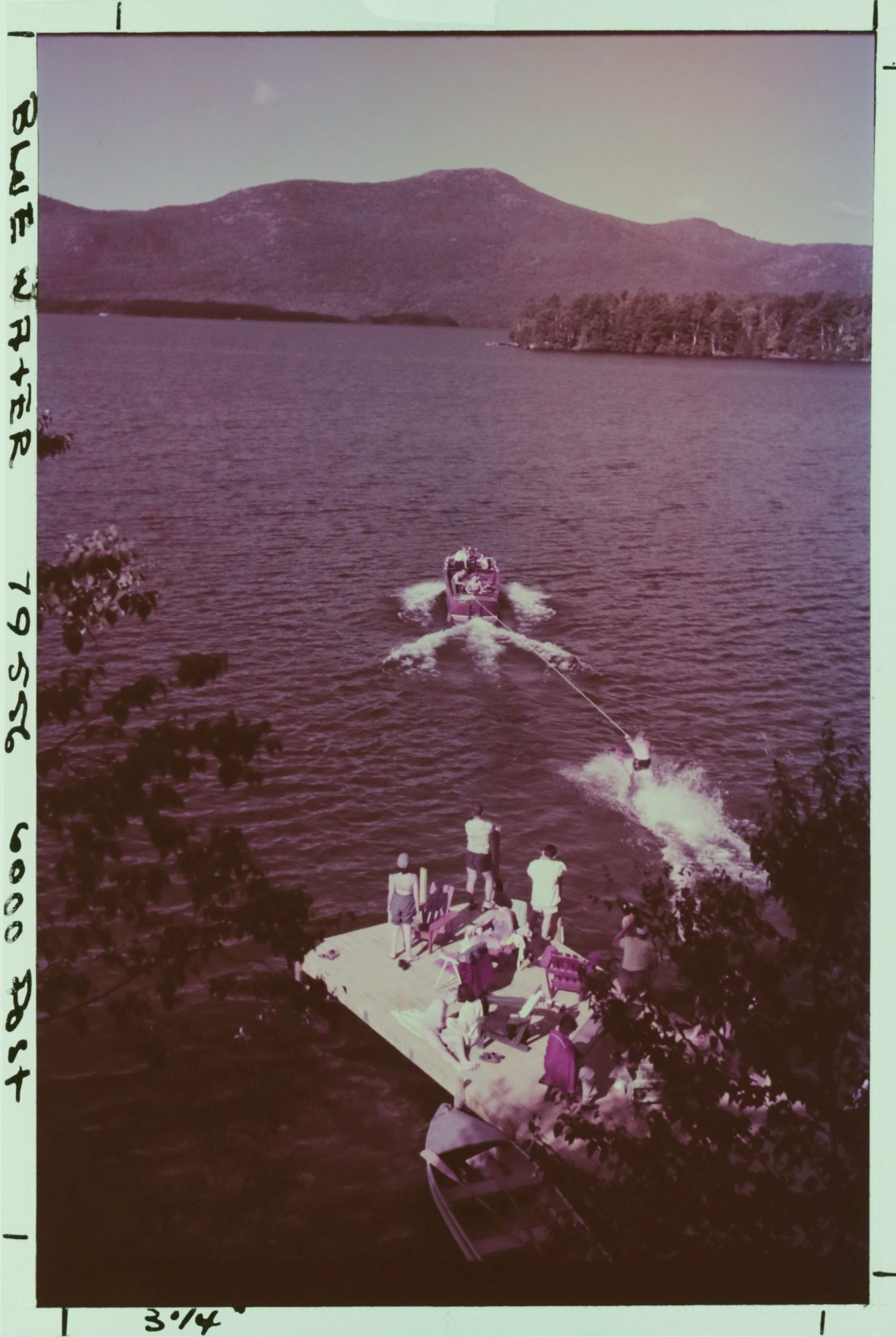 A group of people on a boat in a lake with mountains in the background