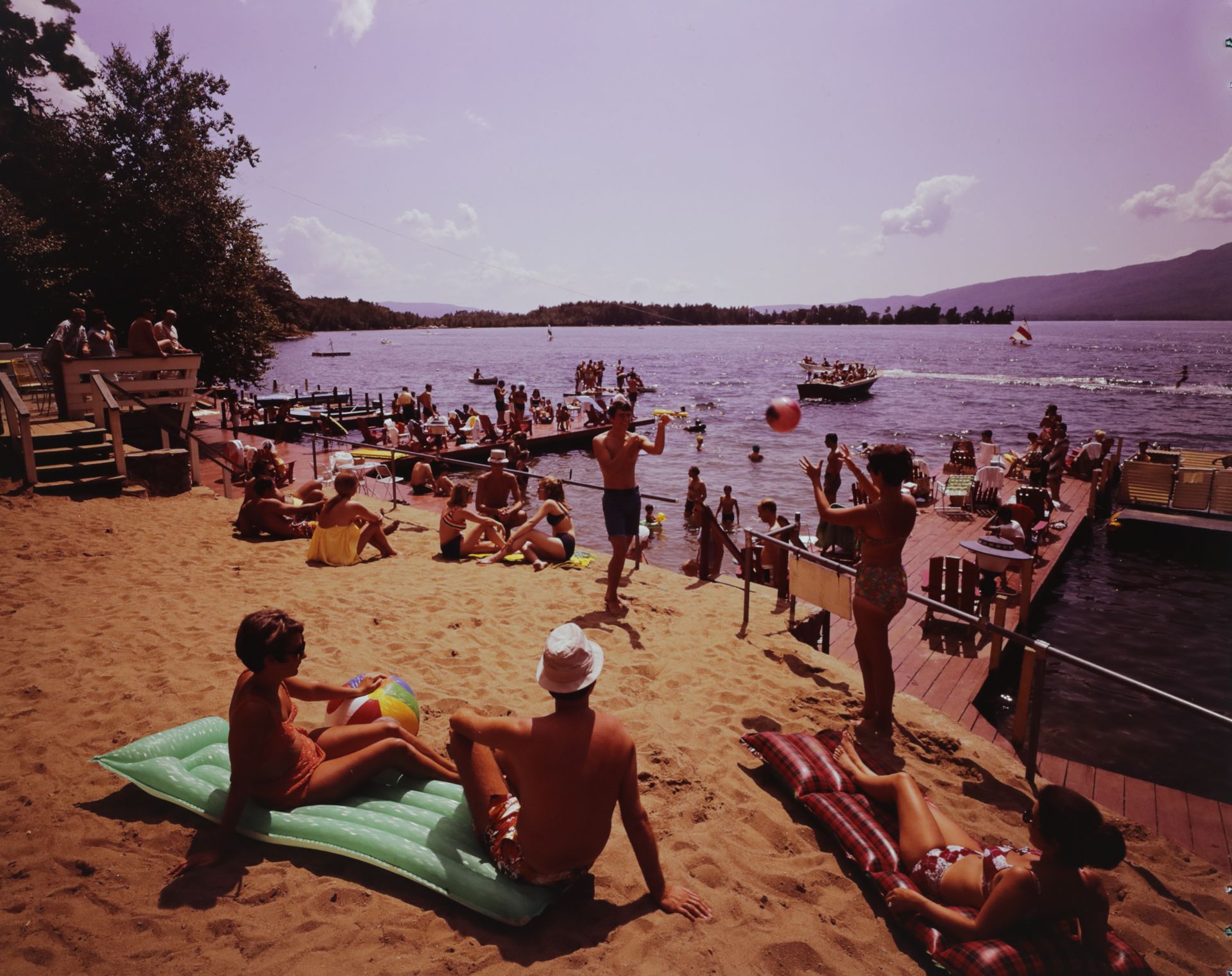 A group of people are sitting on a beach near a body of water