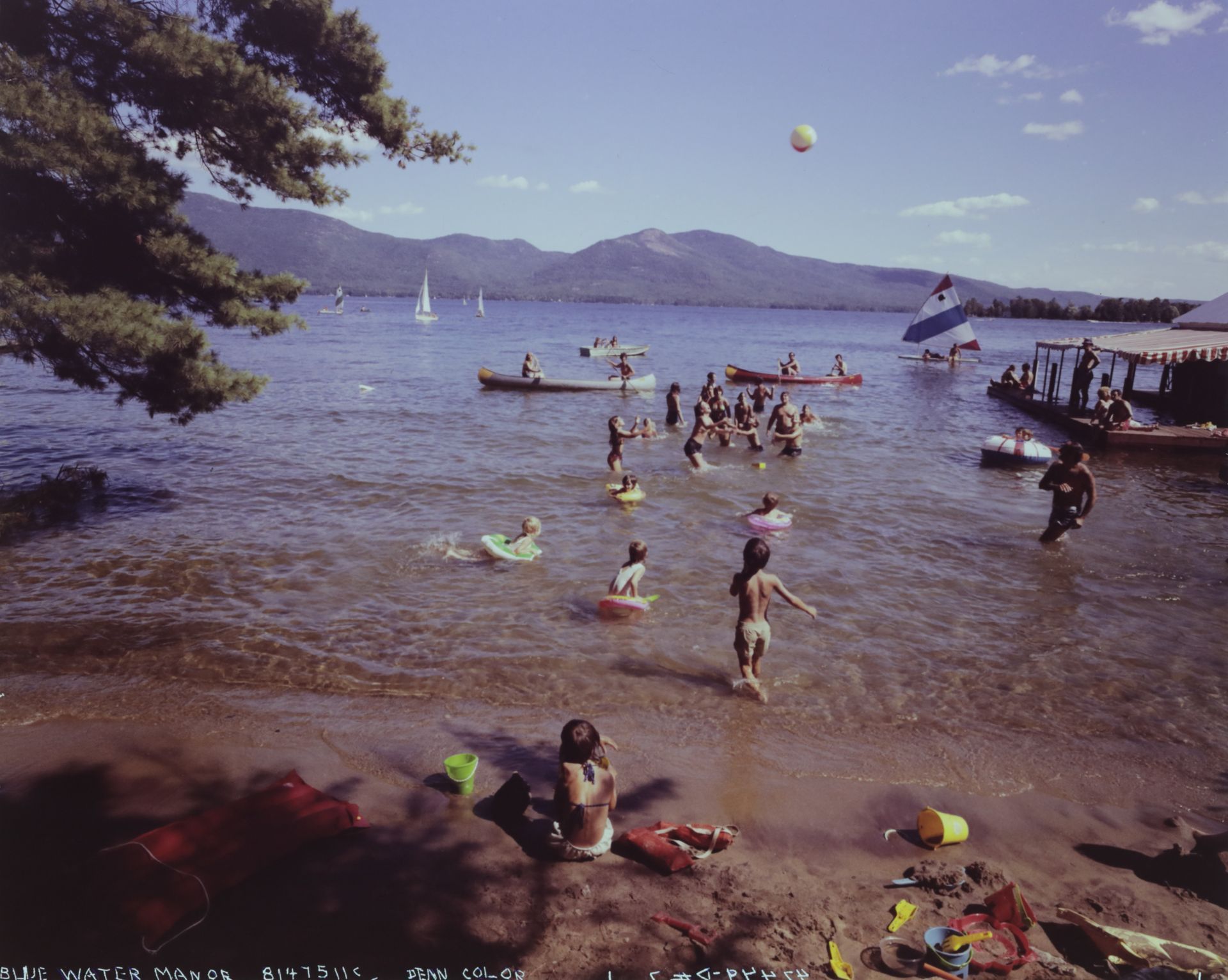 A group of people are playing in a lake with mountains in the background