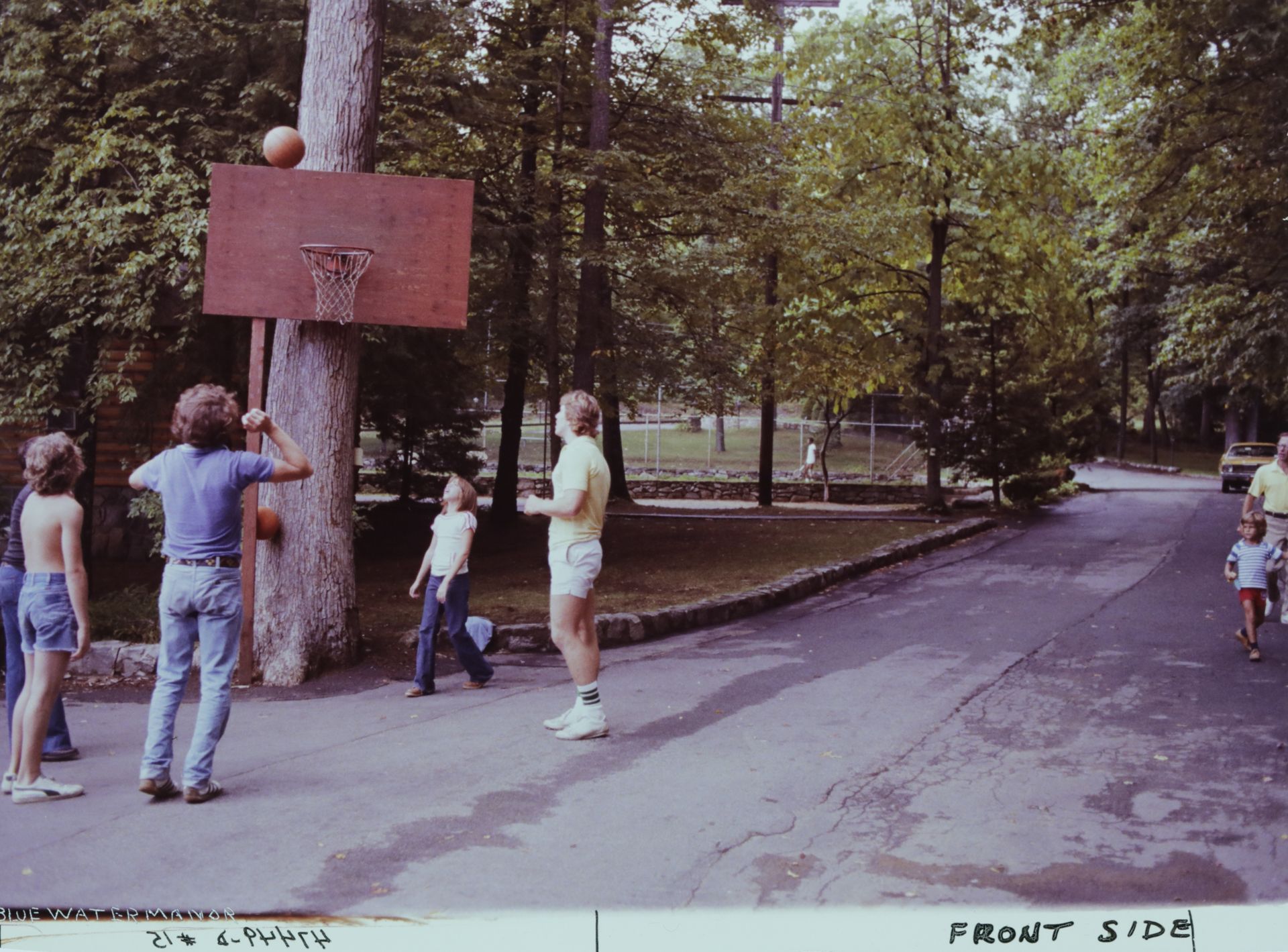A group of people are playing basketball at the old Blue Water Manor hoop