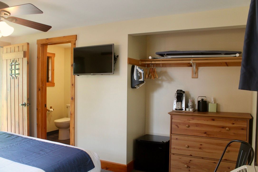 A bedroom with a bed , dresser , television and a ceiling fan.